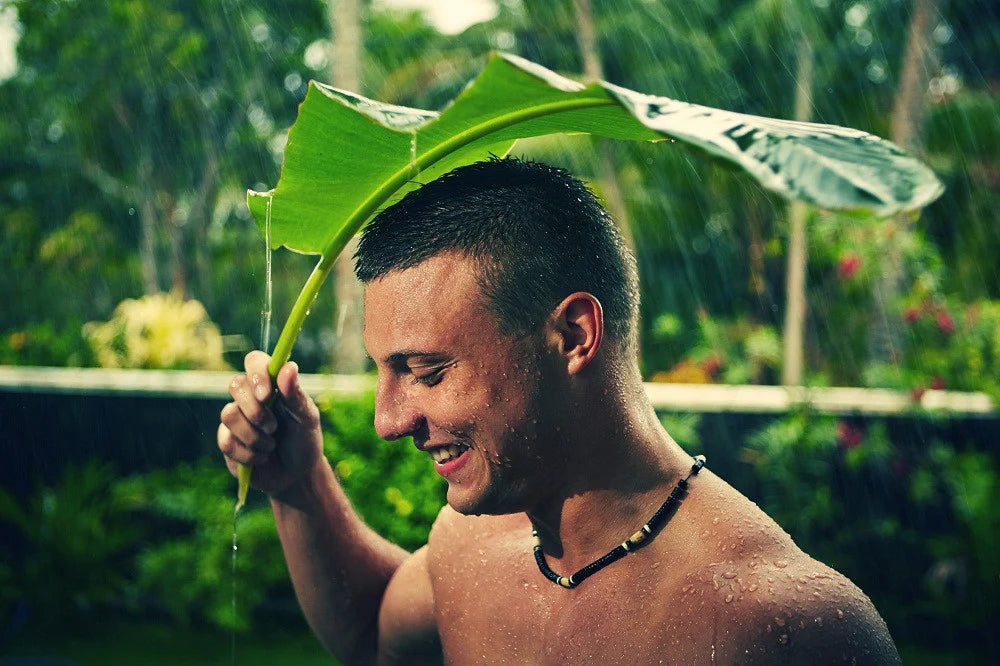 Portrait of a man in natural lighting under a plant, symbolizing the powerful connection between men and plant-based skincare.